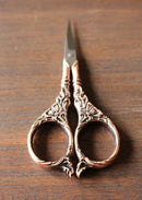 Botanical Garden Scissors in Antique Cooper Finish on wooden surface.