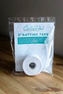 Roll of 2 inch batting tape in a clear packaging with Callie Del branding on a wooden surface.