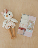 Stuffed Claire toy chicken with floral outfit next to kit packaging on a wooden surface