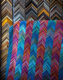 A design from the book Kaffe Fassett's Quilts in London showing woven stripes fabric used in a quilt with a zigzag pattern in front of a wall of picture frames.