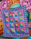 A design from the book Kaffe Fassett's Quilts in London showing a colorful quilt with geometric patterns against a vibrant floral background.