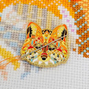 Mandala Fox Enamel Needle Minder on matching cross-stitch design with needle.