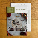 Cross stitch pattern chart and cover titled 'Night Riders' by Love Poppet on a wooden surface.