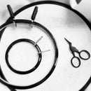 Spring Tension Embroidery Hoops in black color and 3 different sizes shown on white cloth.