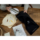 Person holding a black drawstring bag while inserting the Halo Go 2 Rechargeable Table Light and Magnifier.
