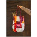 Alamo Tote Patchwork tote bag held by a hand against a dark background.