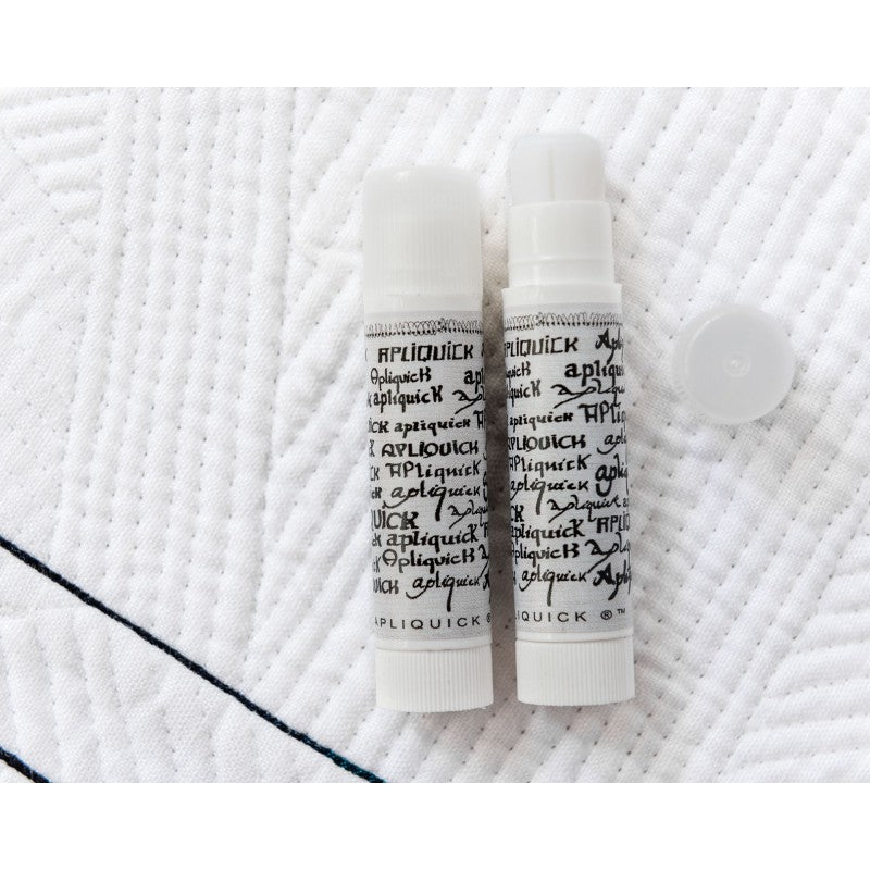 Two white tubes with black text of Apliquick Fabric Glue on a textured white surface.
