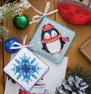 Bead Embroidery Two-Sided Decoration Kit - Sweet Little Penguin shows beaded Christmas ornaments on a wooden surface with festive decorations.