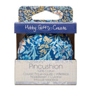 A Blue Floral Pincushion with Wooden Base, presented in its retail box. The box features a blue floral top panel, a blue band with the brand name 'Hobby Gifts Create' in white script, and a light beige lower section with the product name 'Pincushion' and '100% Cotton' printed in black.