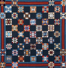 Quilt with a pattern of star-shaped blocks in red, blue, and white from Bonnie Hunter's Scrap-Savvy Quilting.