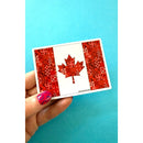 Hand holding a Canada Quilt Sticker with a Canadian Flag design on a blue background