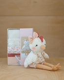 Plush Clair toy chicken with a bow and floral outfit next to the kit packaging box on a wooden surface.