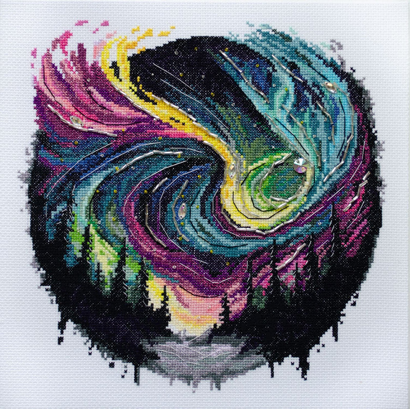 Cross Stitch Kit  Night Glow shows aurora borealis above evergreens and iced river.
