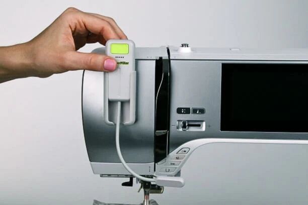 Hand placing a Cutterpillar Flex Sewing Machine Light onto a sewing machine.
