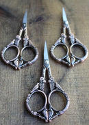 Feathered Friends Scissors in Antique Copper Finish on wooden surface