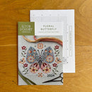 Floral Butterfly Cross Stitch pattern chart and pattern cover on wooden surface.