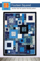 Fourteen Squared Quilt with blue and white squares on a white wall.
