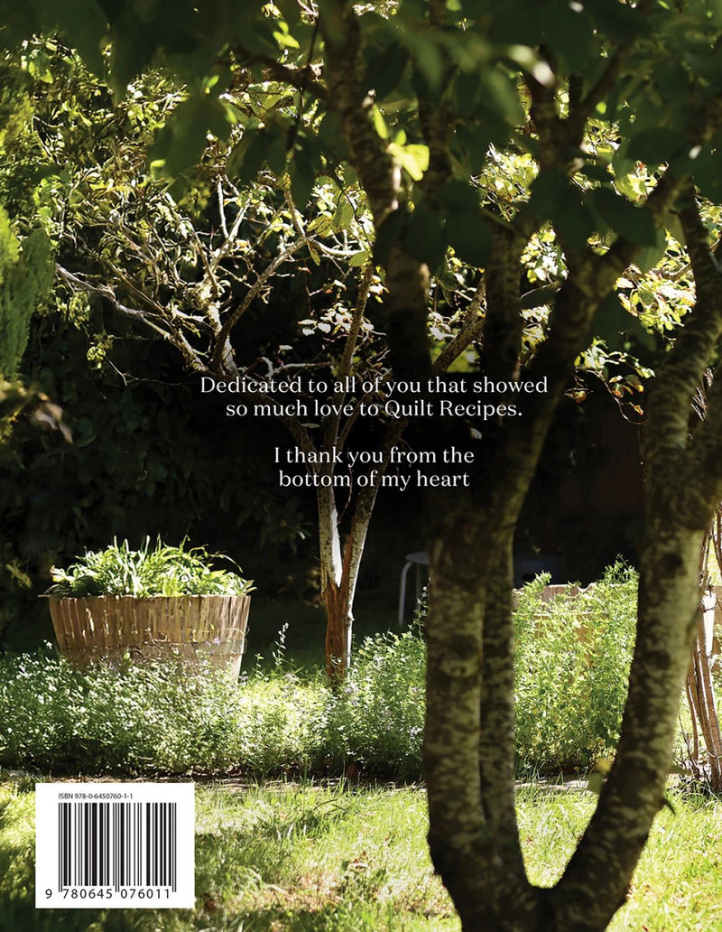 Garden scene with trees and plants, featuring a dedication message on back of book cover for Gathered - Quilt Recipes 2.