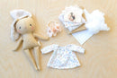 Stuffed Jeanne bunny doll with a dress and accessories on a wooden surface 