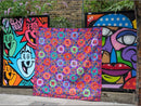 A design from the book Kaffe Fassett's Quilts in London showing two colorful abstract wall artworks displayed with a quilt outdoors.