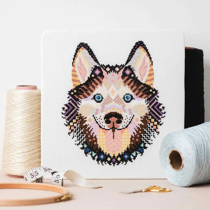 Mandala Husky Cross Stitch Pattern upright on table with thread, hoop, and scissors.