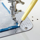 Metal Hera with Stylus holding fabric down on sewing machine needle plate.