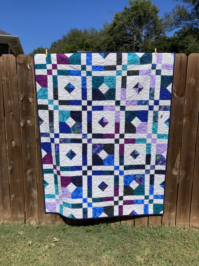 nine carat quilt cut loose press picture of quilt on fence