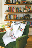 Pattern from "Not Your Typical Jelly Roll Quilts" shows green chair with a butterfly quilt draped over it, in front of a bookshelf filled with books and decorative items.