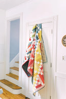 Pattern from "Not Your Typical Jelly Roll Quilts" shows colorful quilt hanging on a white door with wooden stairs in the background.