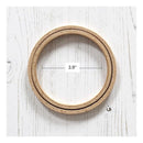 Wooden embroidery hoop with measurement label on a white wooden surface