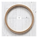 A natural wood embroidery hoop shown on a white wood plank background, with a measurement overlay indicating a diameter of 7.5 inches.