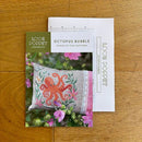 Octopus Bubble Cross Stitch Pattern shows an octopus stitch chart on a wooden surface