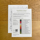 Cross stitch pattern chart for 'Pumpkin Toad' on a wooden surface