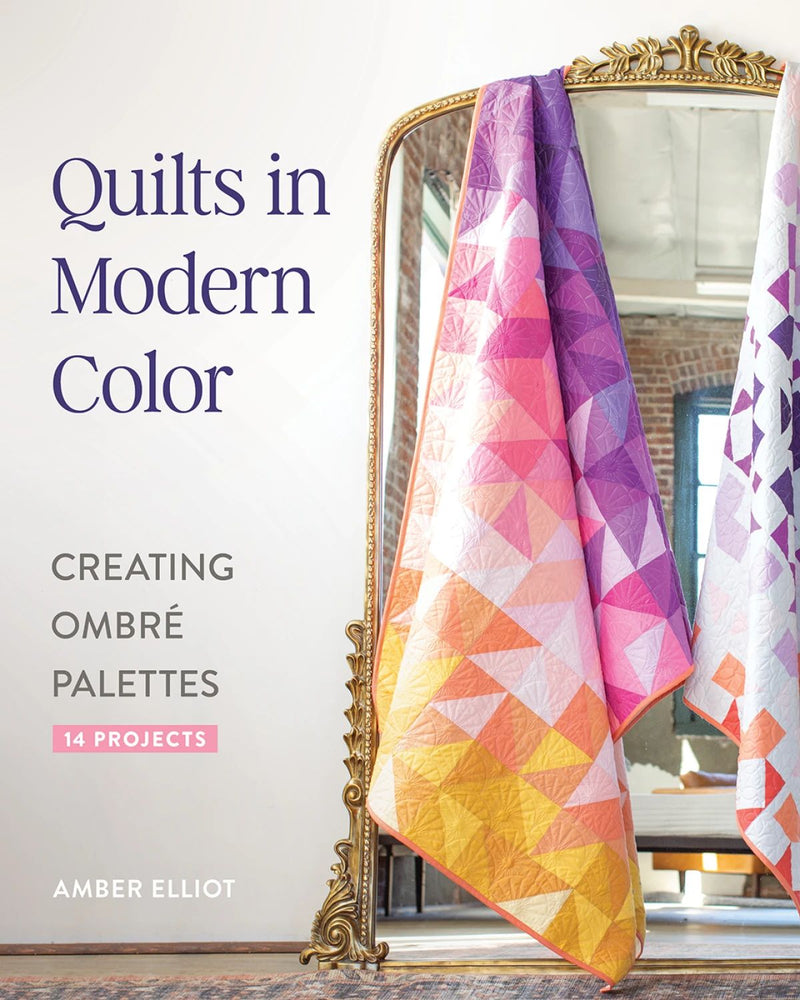 Book cover of "Quilts in Modern Color" with a colorful quilt displayed in front of a mirror.