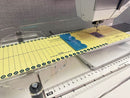 Sewing machine with a ruler and cutting guide on the Sew Steady Custom Large Deluxe 2.0 Extension Table.