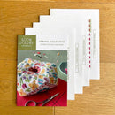 Spring Biscournu Cross Stitch Pattern on a wooden surface