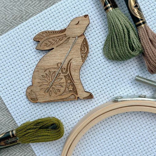Stargazing Hare Needle Minder on aida cloth with floss and hoop.