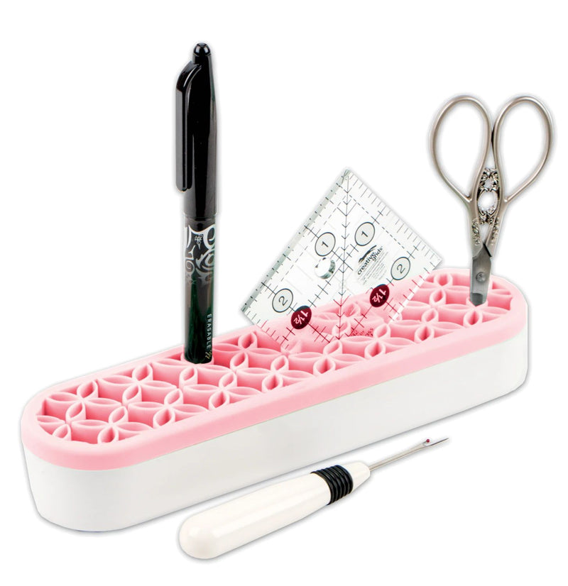 Stash 'n Store shown in pink with pen, ruler, scissors, and seam ripper.