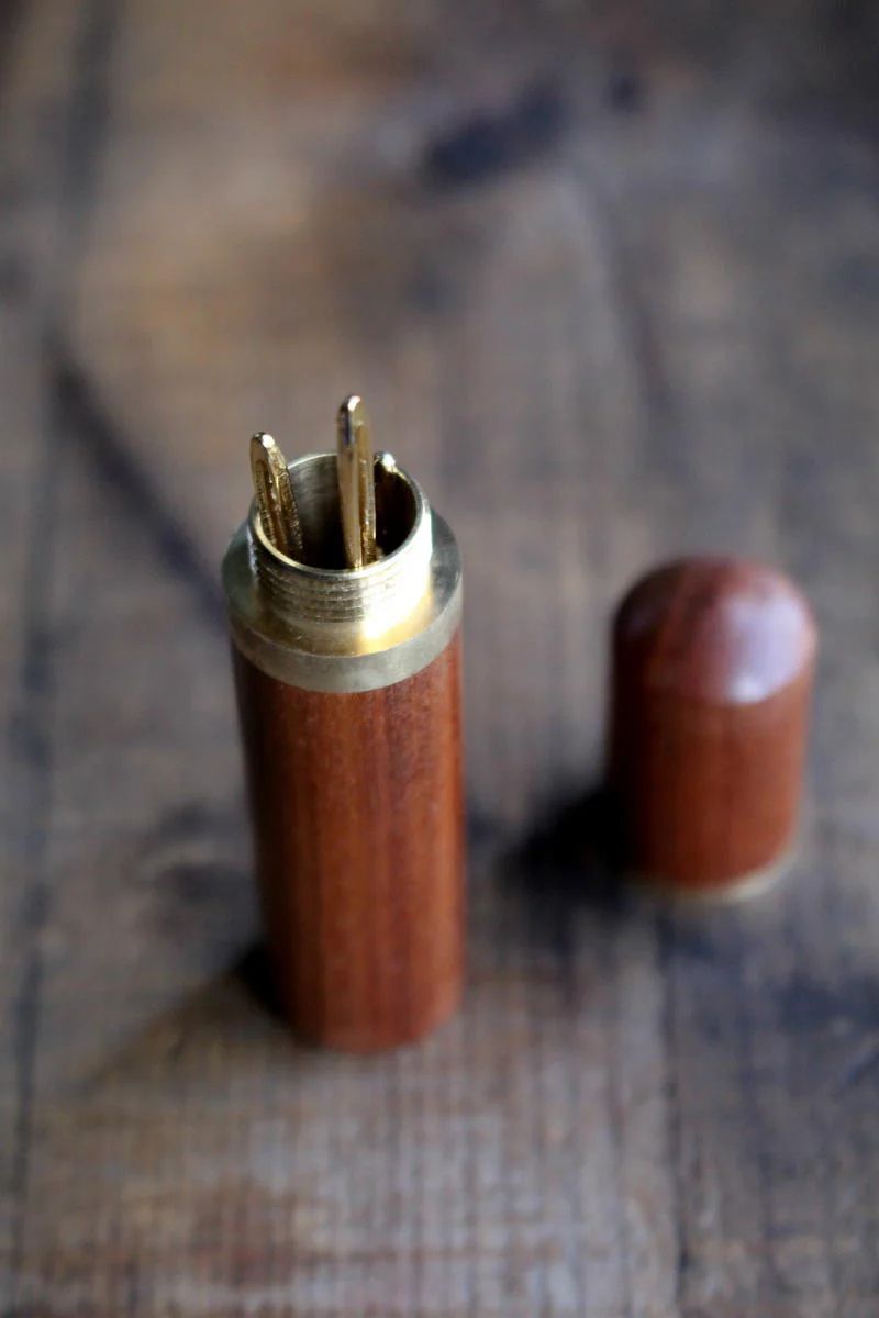Sandalwood  Needle Case with Tapestry Needles on wooden surface.