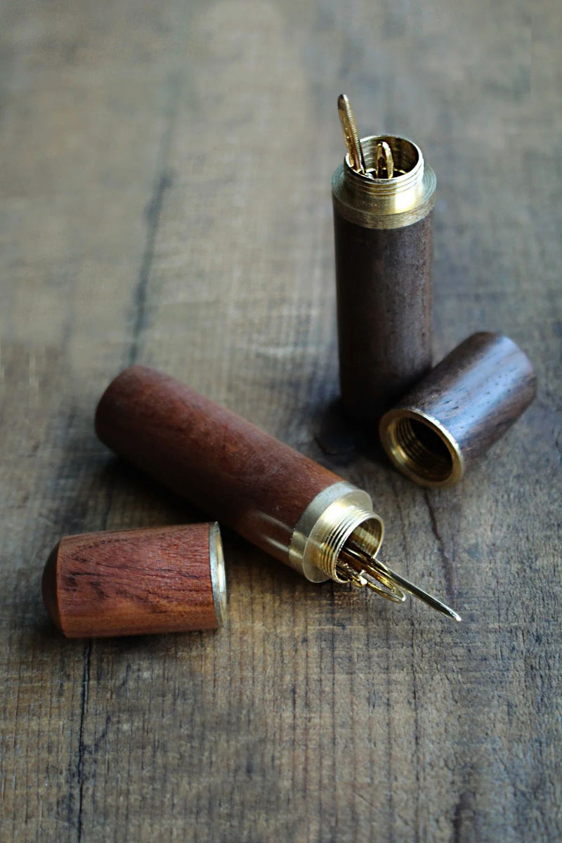 Wooden Needle Case with Tapestry Needles on wooden surface uncapped..