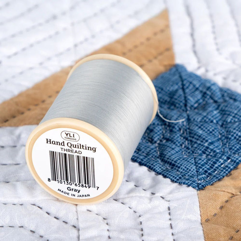 YLI Hand Quilting Thread 40 wt  3-ply 457 m (500 yd.) spool - Grey 011 showing bottom of spool