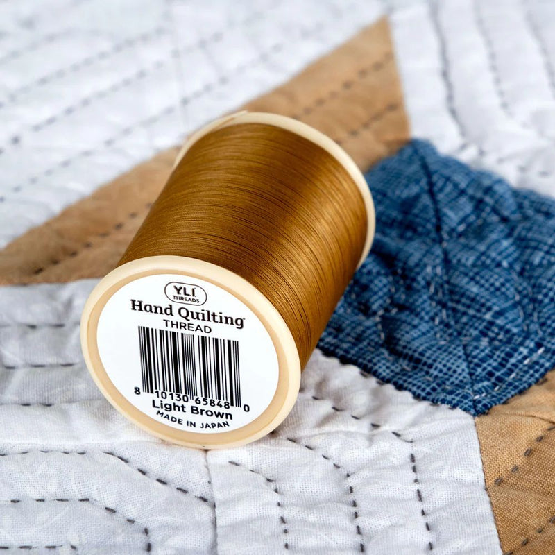 YLI Hand Quilting Thread 40 wt  3-ply 457 m (500 yd.) spool - Light Brown 003 showing bottom of spool